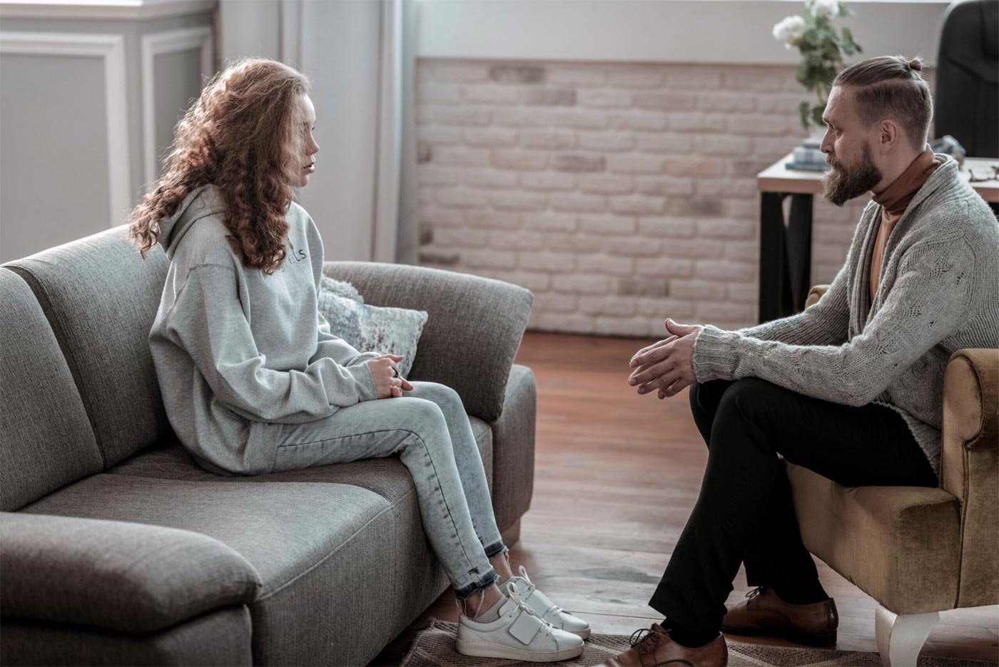 Counselor after school. Beautiful stylish girl wearing jeans and grey hoodie visiting counselor after school
