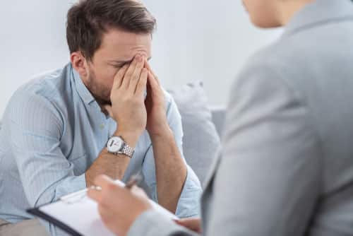 a handsome young man with mental health problem feeling sad during therapy session with a counselor