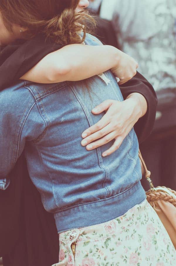 a happy woman wearing denim jacket hugging her best friend