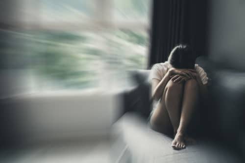 a woman with mental health problem feeling depressed and anxious sitting in a sofa crying