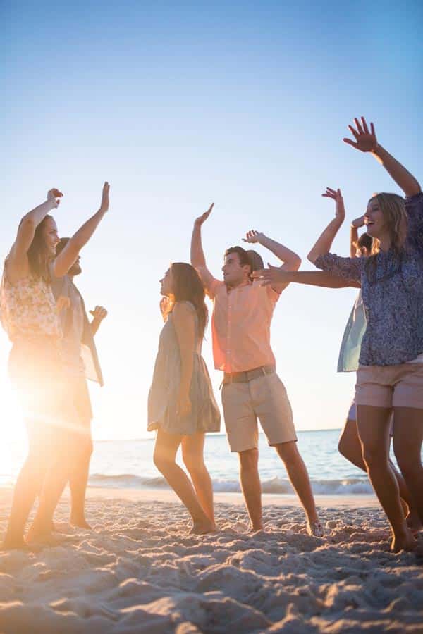 group of friends hanging out, dancing at the beach