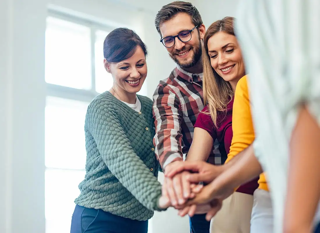 Smiling people from the group therapy, holding hands together, one over the other