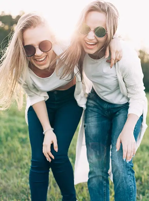 Two young women are having fun on the green field