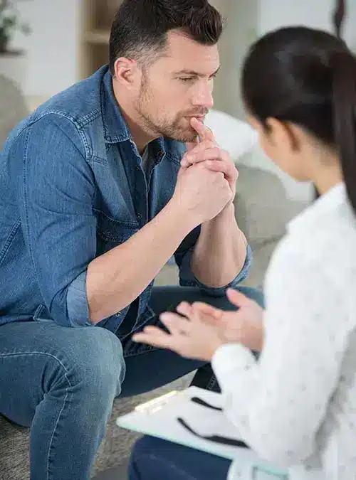 counselor taking notes while analyzing young man