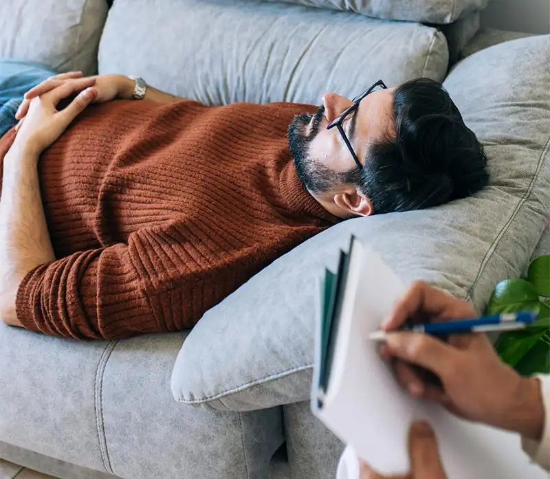 A man lying on a couch, head on a pillow, reflecting the impact of major depressive disorder treatment