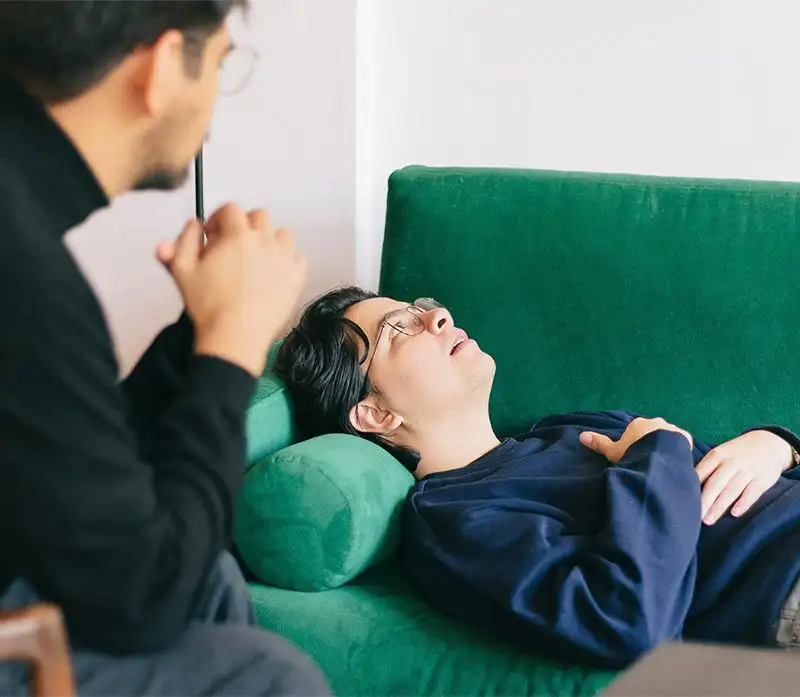 a male client lies on a couch, illustrating a supportive environment for individuals undergoing PTSD treatment.