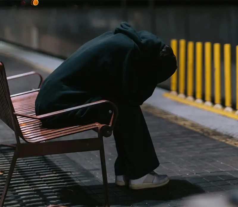 a person sitting on a bench isolating herself from the crowd, social anxeity disorder concept (1)